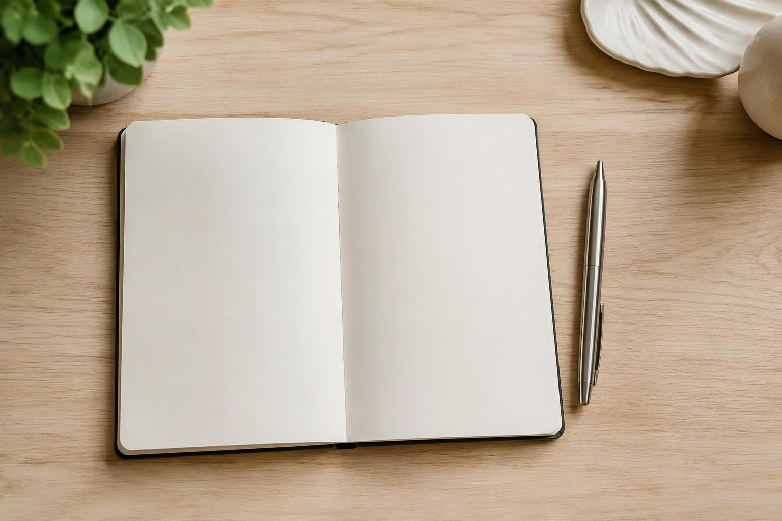 Caderno aberto com páginas em branco e uma caneta sobre a mesa.